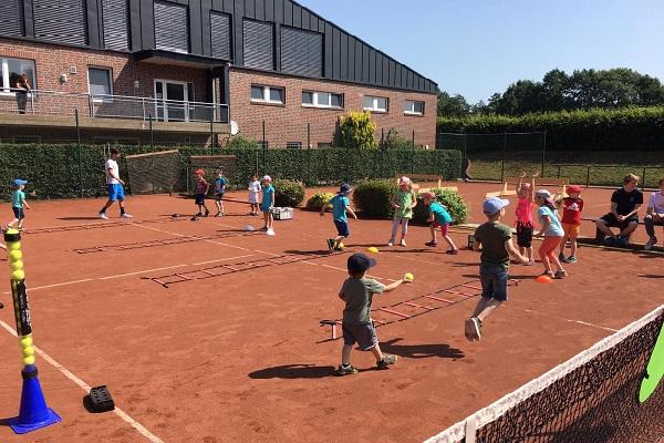 Eine große Gruppe Tenniskinder trainiert spielerisch auf Außenplatz 2.